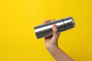 Woman holding modern thermos on yellow background, closeup