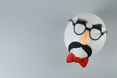 Photo of Man's face made of balloon, funny mask with fake mustache, nose and glasses on grey background, top view. Space for text