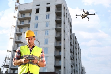 Builder operating drone with remote control at construction site. Aerial survey