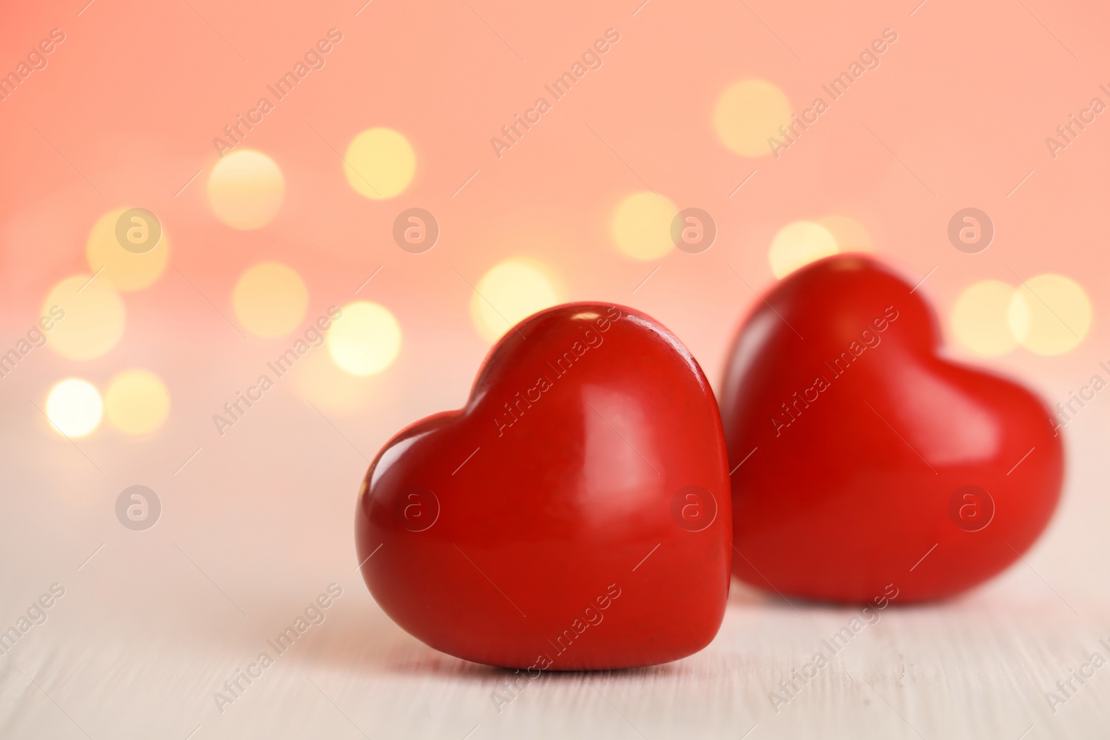 Photo of Red hearts on white wooden table against festive lights. St. Valentine's day