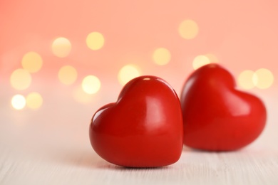 Photo of Red hearts on white wooden table against festive lights. St. Valentine's day