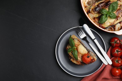 Photo of Plate of delicious eggplant lasagna served on black table, flat lay. Space for text