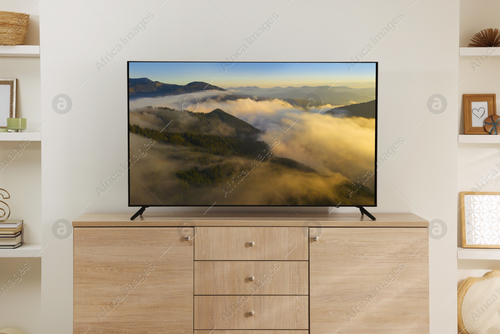 Image of Modern TV set on wooden stand in room. Scene of nature themed movie on screen