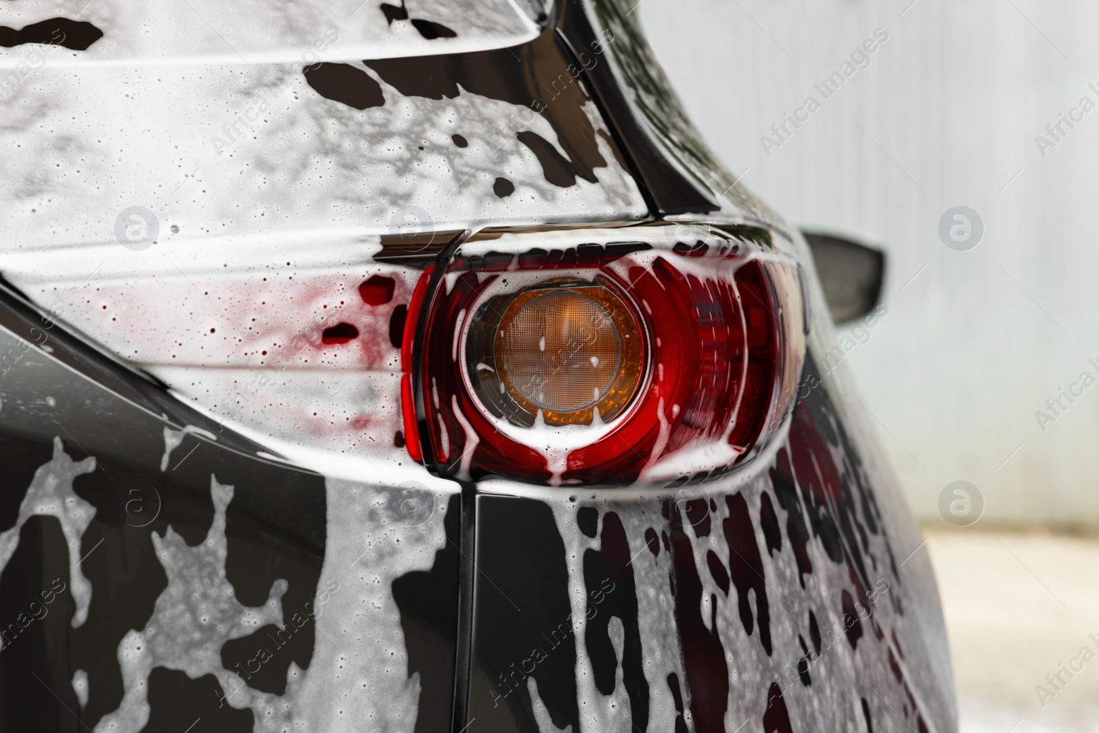 Photo of Auto with cleaning foam at car wash, closeup