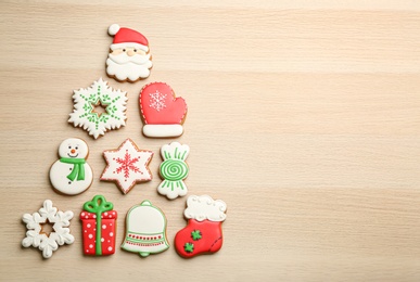 Photo of Christmas tree shape made of delicious gingerbread cookies on wooden table, flat lay. Space for text