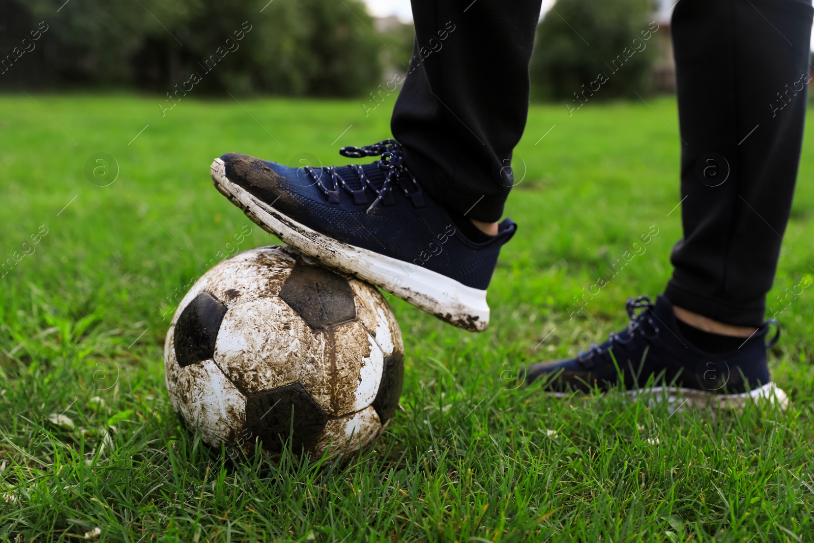 Photo of Man with dirty soccer ball on green grass outdoors, closeup