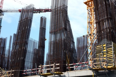 Tower cranes near building under construction against blue sky