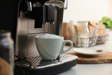 Photo of Modern coffee machine making cappuccino in kitchen, space for text
