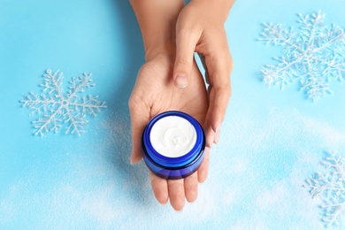 Photo of Woman holding jar of moisturizing cream on color background. Winter skin care cosmetic