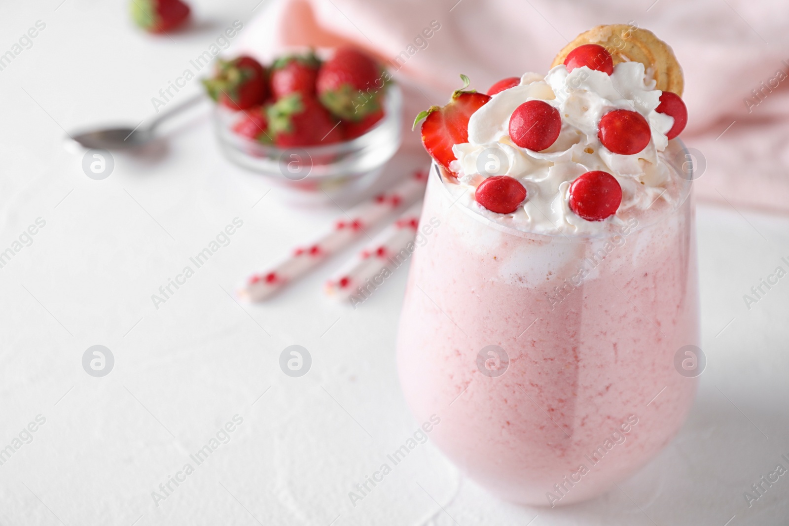 Photo of Tasty strawberry milk shake in glass on white table. Space for text