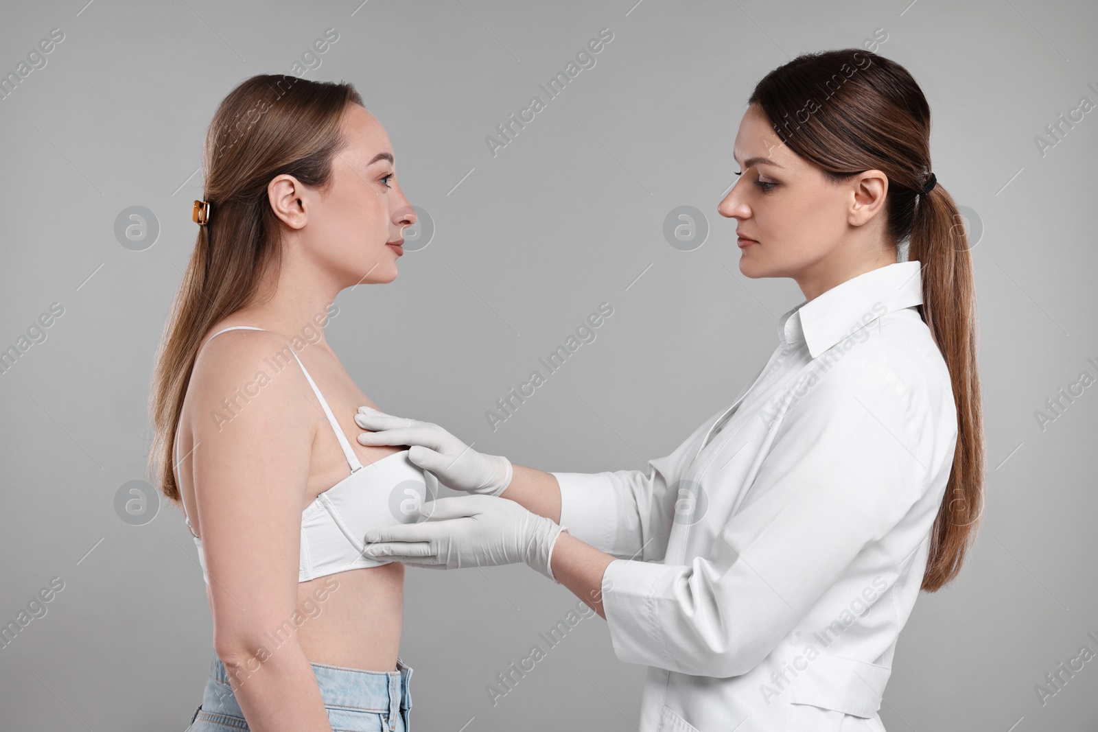 Photo of Mammologist checking woman's breast on gray background