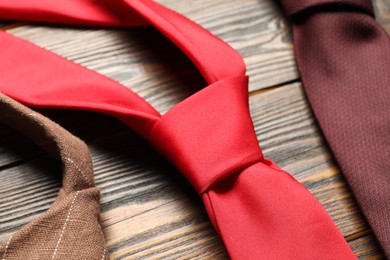 Photo of Different neckties on wooden table, closeup view