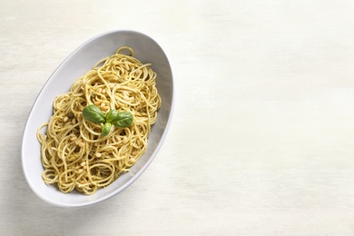 Plate of delicious basil pesto pasta on white background, top view with space for text