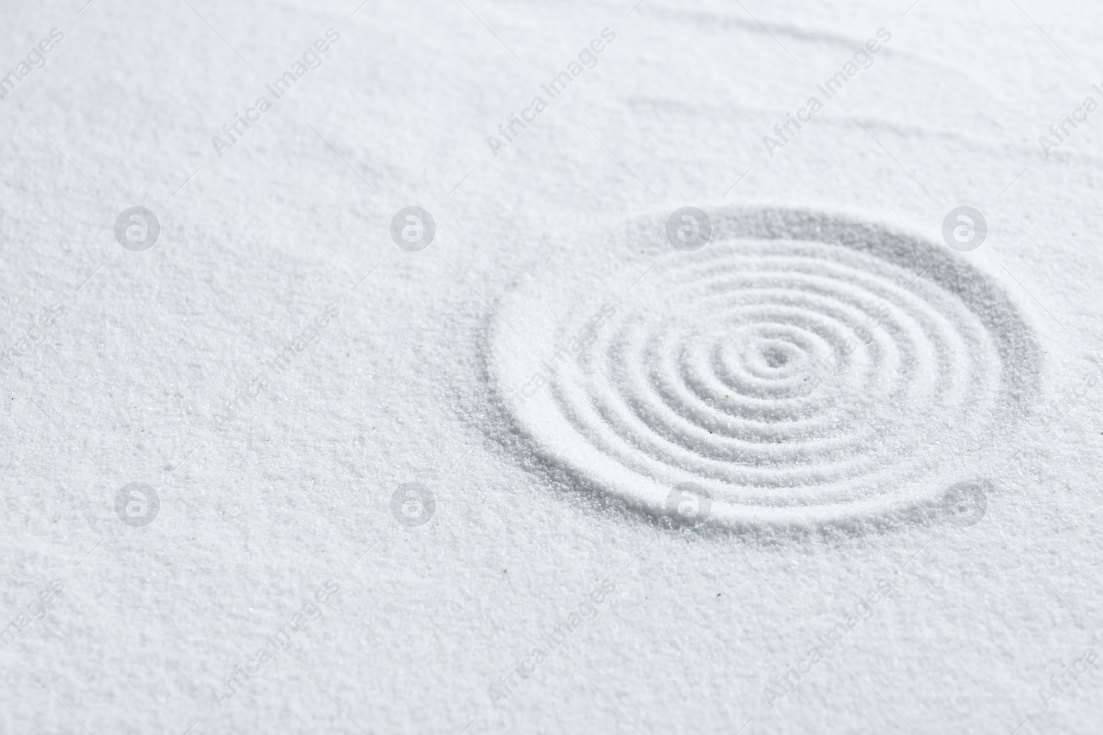 Photo of Zen rock garden. Circle pattern on white sand, closeup. Space for text