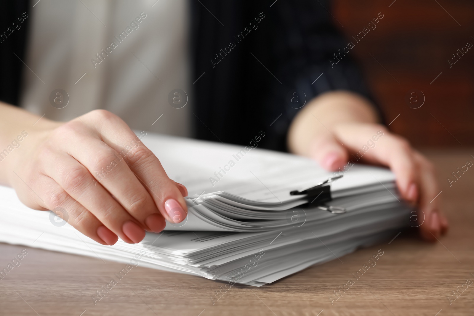 Photo of Woman reading documents at wooden table in office, closeup