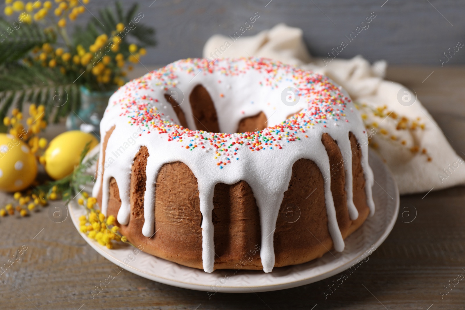 Photo of Glazed Easter cake with sprinkles on wooden table