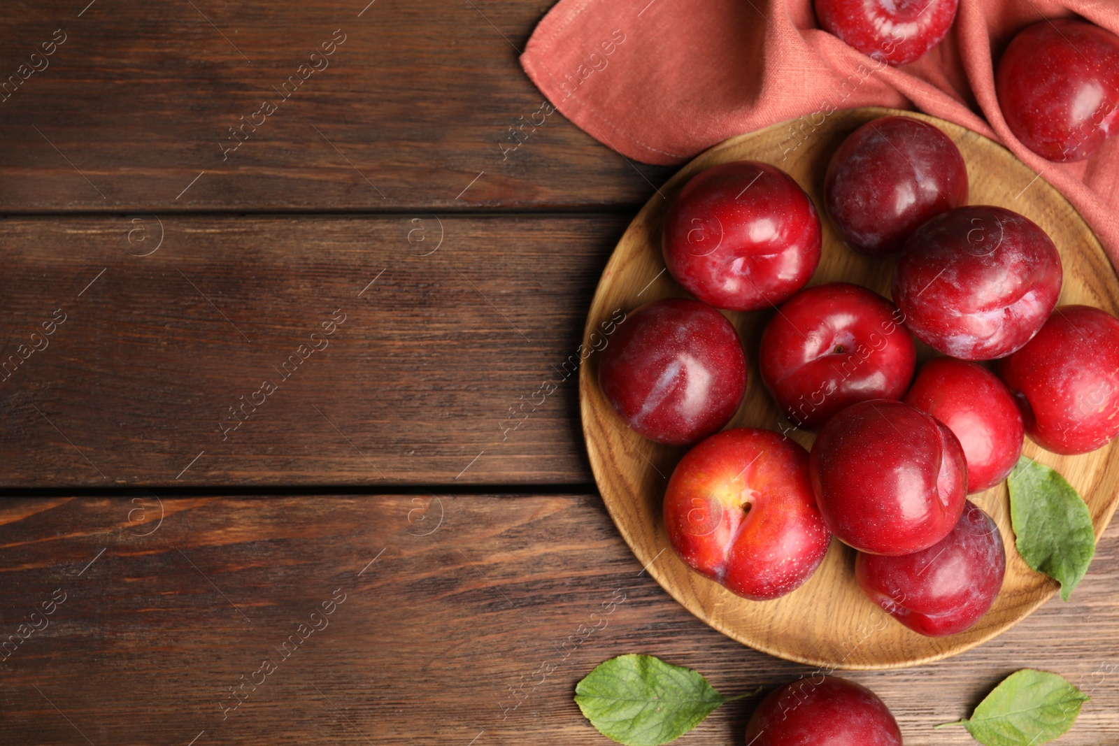 Photo of Delicious ripe plums on wooden table, flat lay. Space for text