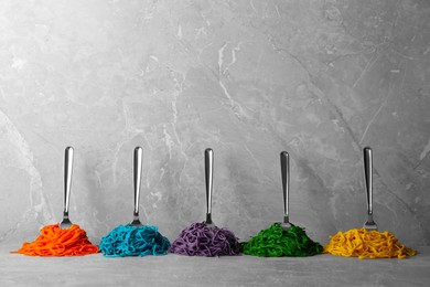 Photo of Spaghetti painted with different food colorings and forks on light grey table