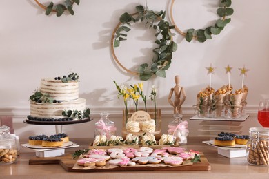 Photo of Baby shower party. Different delicious treats on wooden table indoors