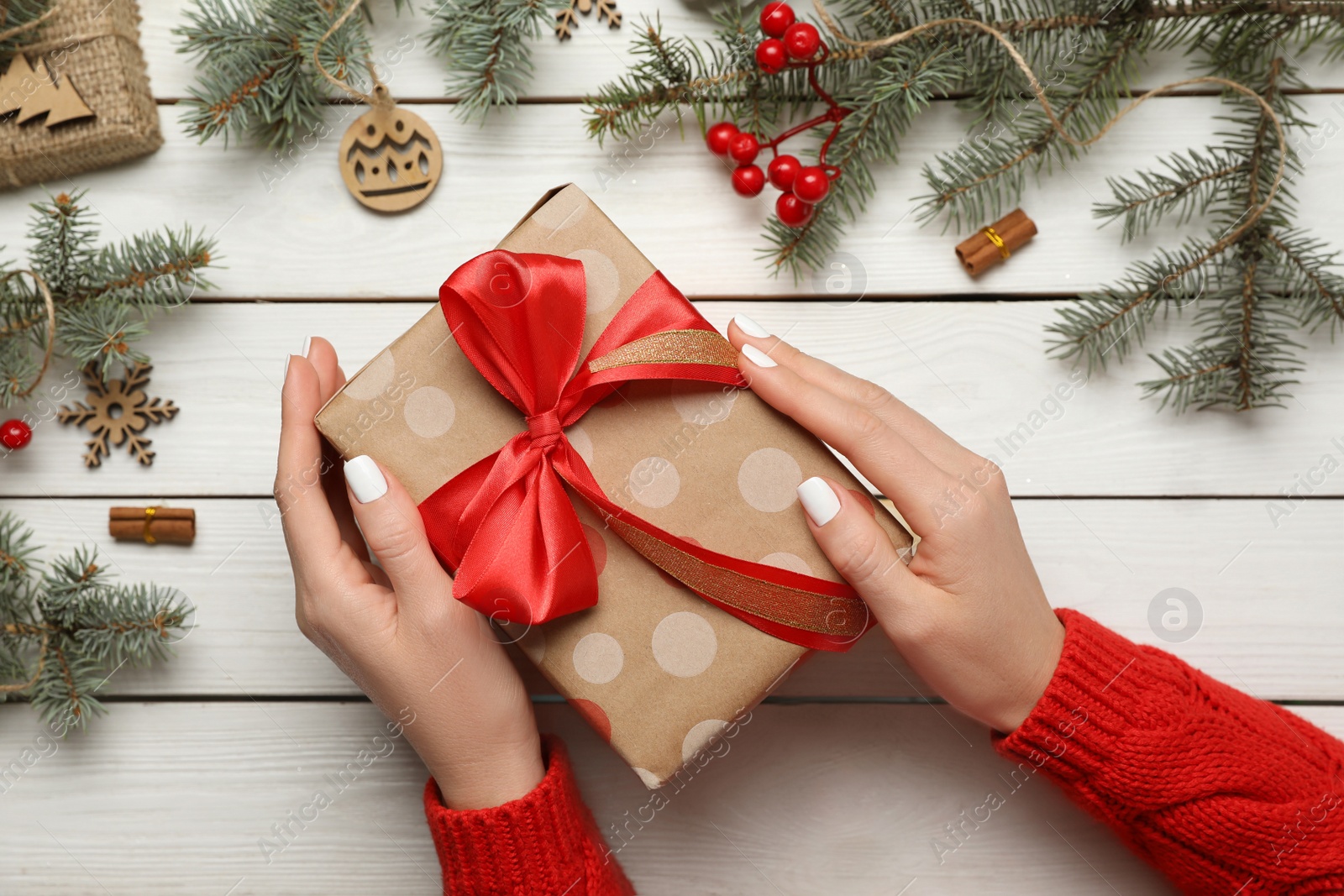 Photo of Woman with Christmas gift at white wooden table, top view