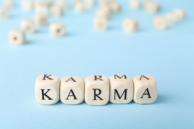 Photo of Word Karma made of cubes with letters on light blue background