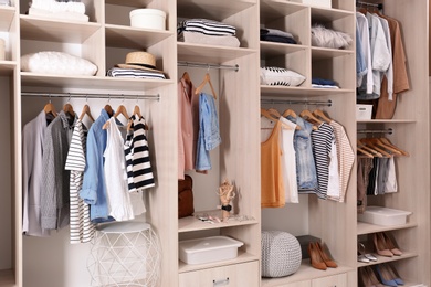 Photo of Stylish clothes, shoes and home stuff in large wardrobe closet