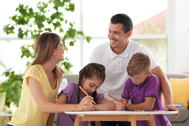 Children with parents drawing at table indoors. Happy family