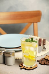 Glass of lemonade and leaf shaped cup coasters on grey wooden table