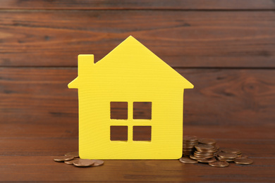 House model and coins on wooden background