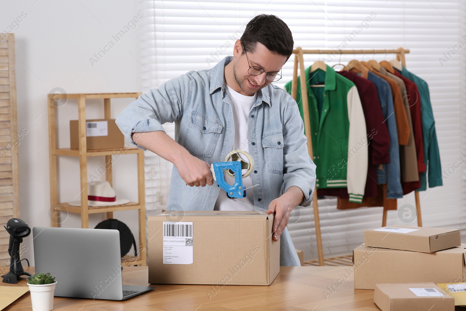 Photo of Seller taping parcel at workplace in office. Online store