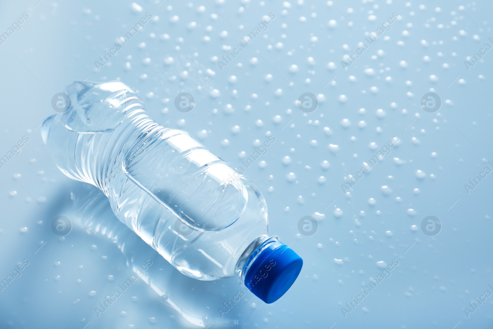 Photo of Bottle of water on wet light surface. Space for text