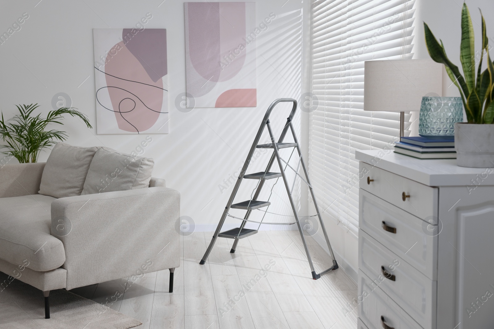 Photo of Metal ladder, couch and chest of drawers in living room