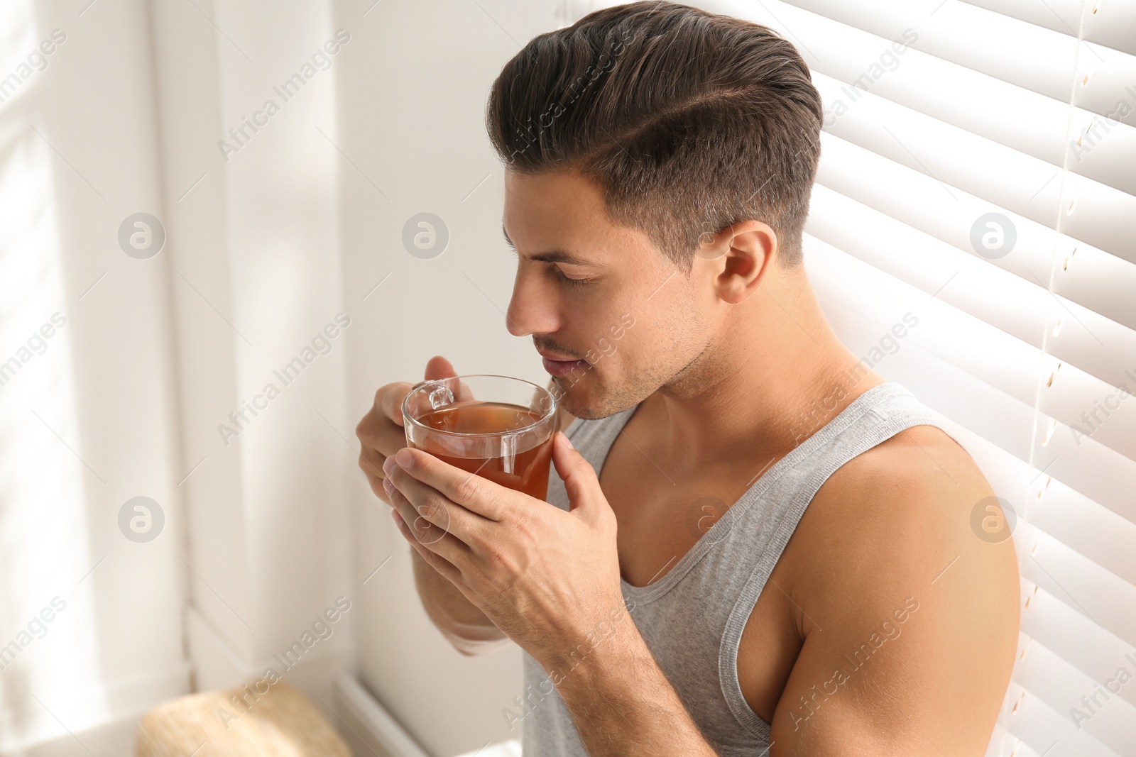 Photo of Man with cup of tea near window. Lazy morning