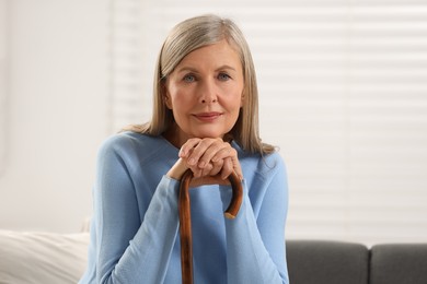 Photo of Mature woman with walking cane on sofa indoors
