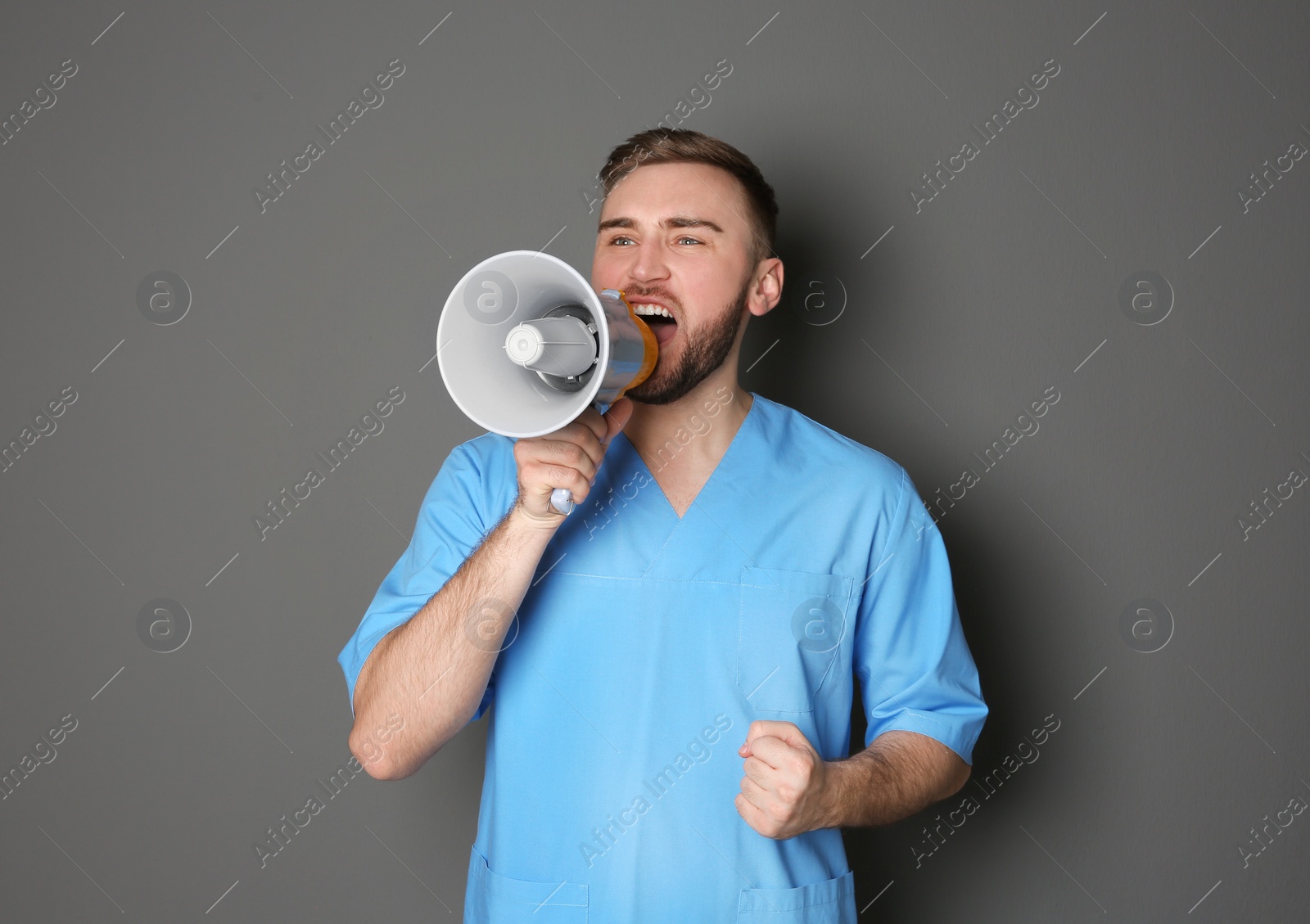 Photo of Male doctor shouting into megaphone on grey background