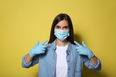 Photo of Female volunteer in mask and gloves on yellow background. Protective measures during coronavirus quarantine