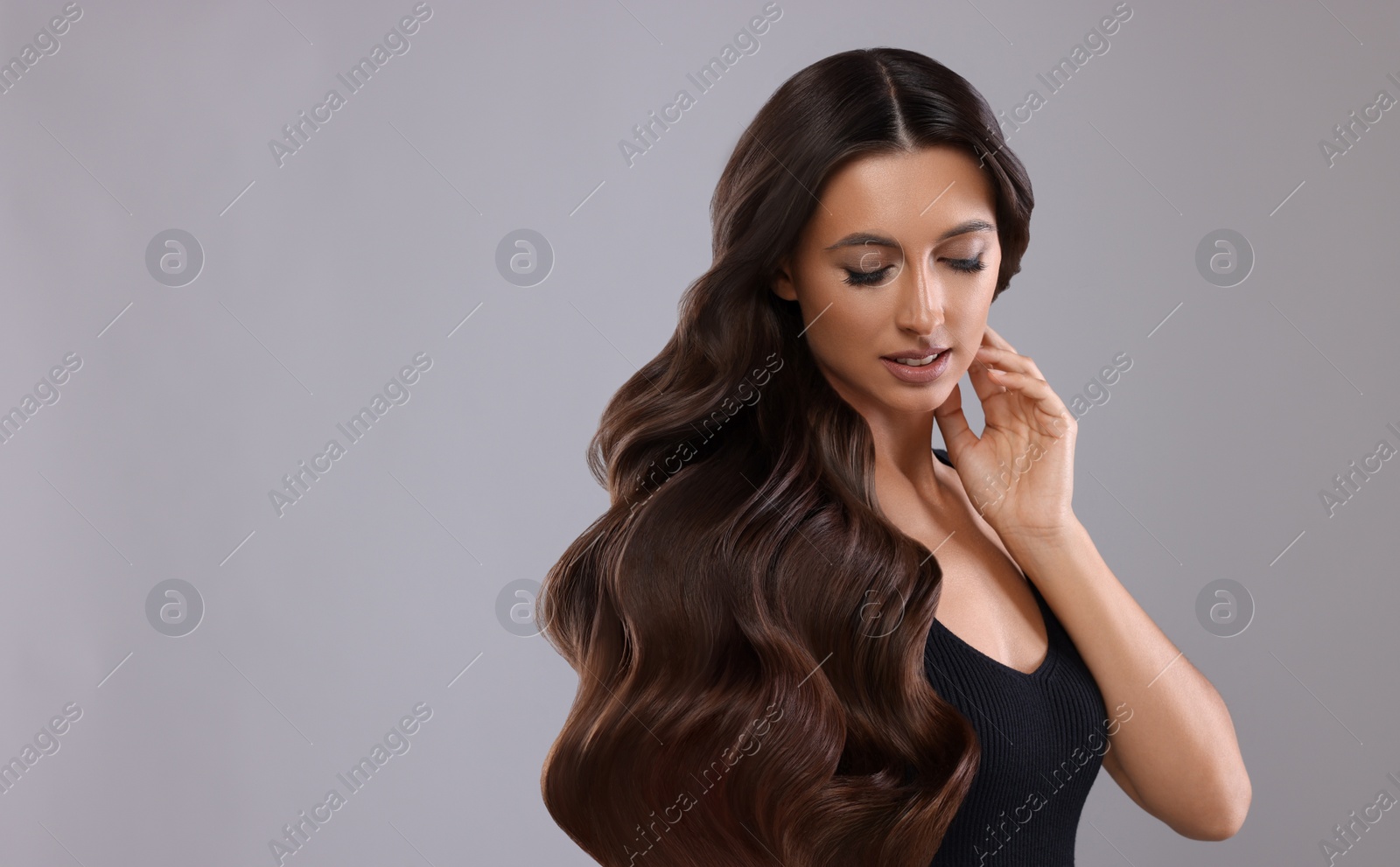 Image of Hair styling. Attractive woman with wavy long hair on grey background, space for text