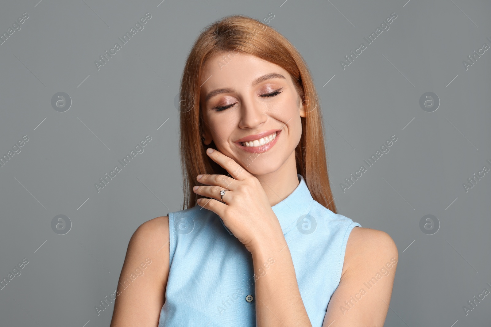 Photo of Happy woman with engagement ring on light grey background