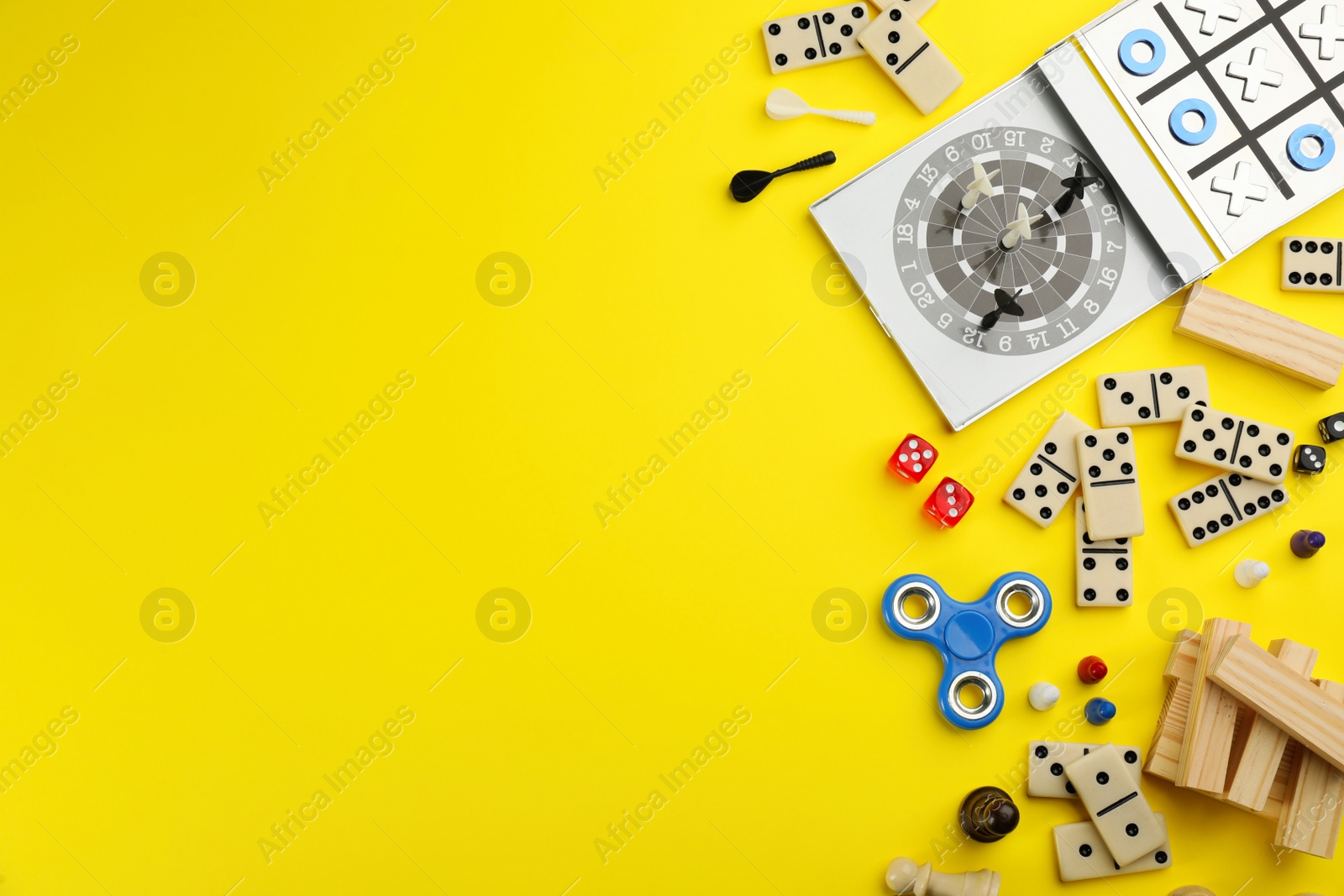 Photo of Different types of board games and its' components on yellow background, flat lay. Space for text