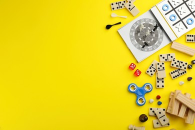 Photo of Different types of board games and its' components on yellow background, flat lay. Space for text