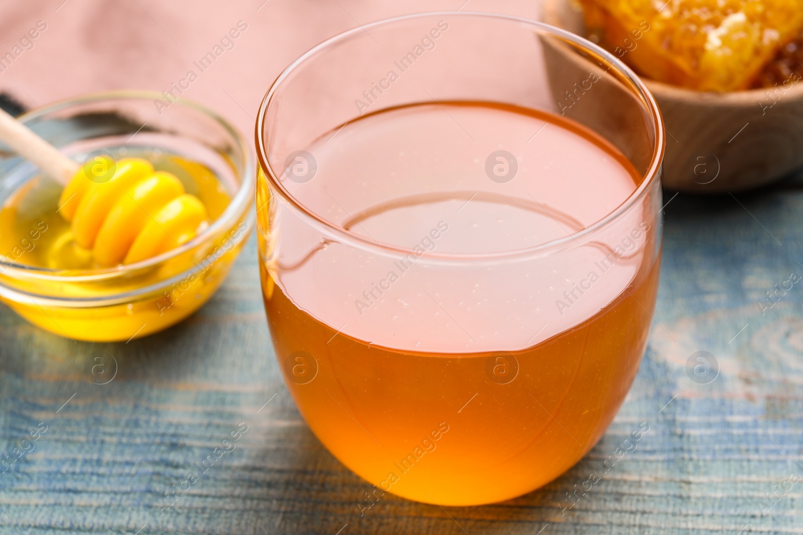 Photo of Tasty honey on light blue wooden table, closeup