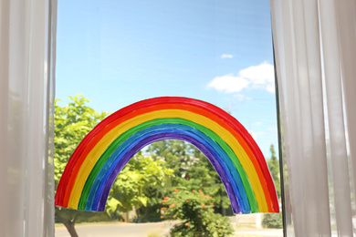 Painting of rainbow on window indoors. Stay at home concept