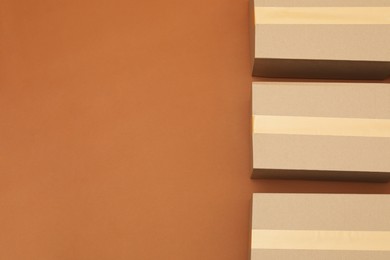 Photo of Cardboard boxes on brown background, flat lay. Space for text