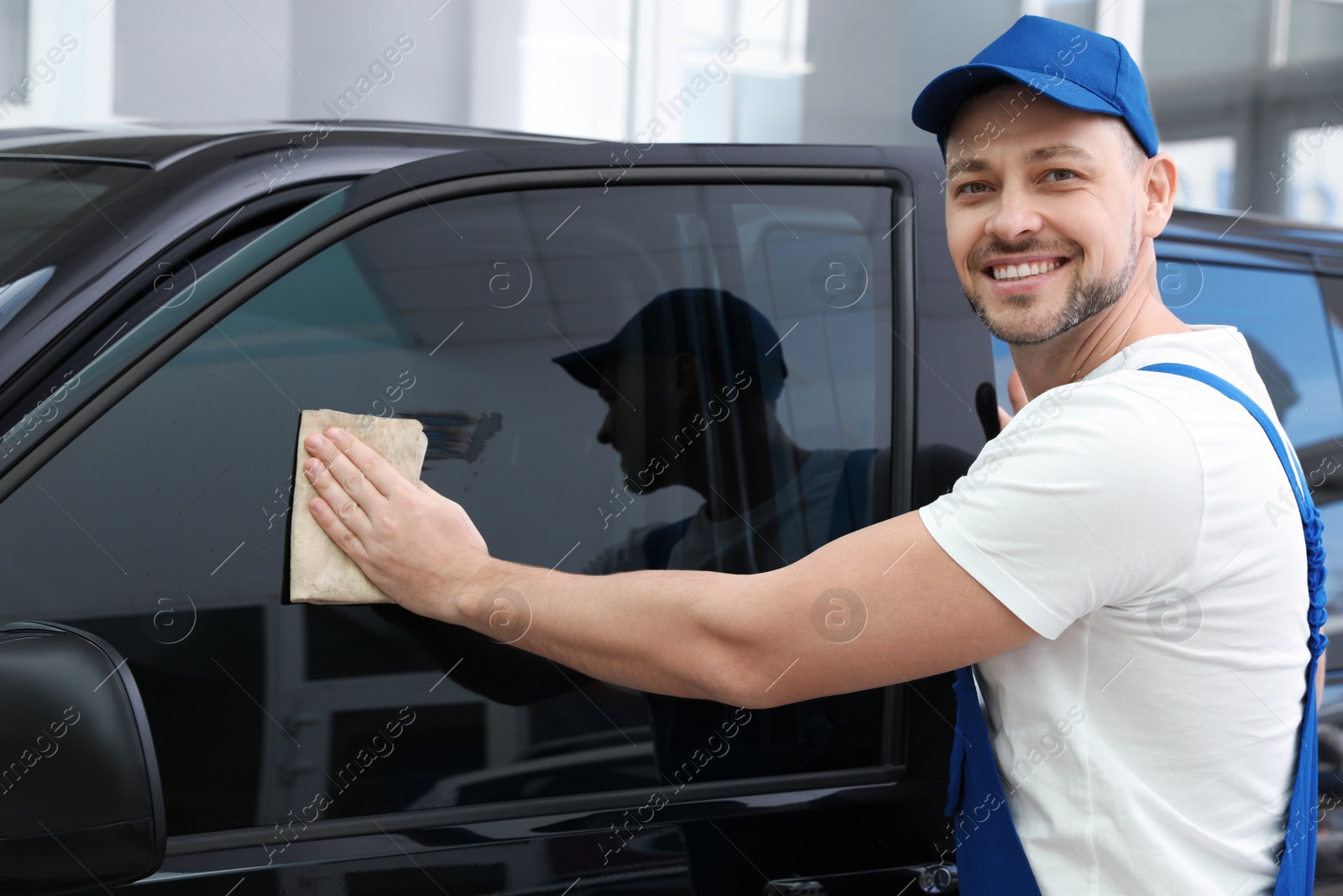 Photo of Worker tinting car window with foil in workshop