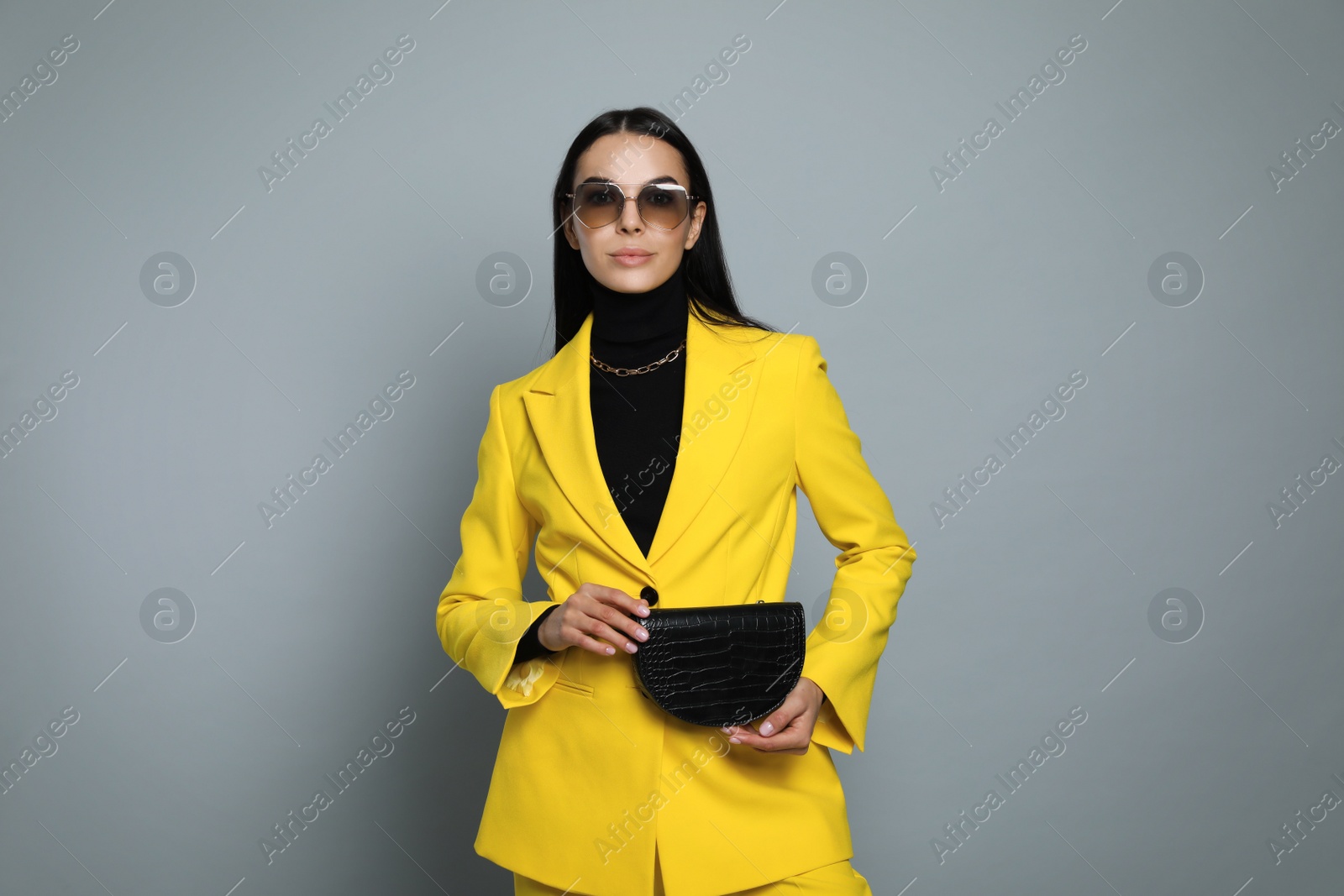 Photo of Beautiful young woman with stylish waist bag on grey background