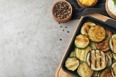 Photo of Flat lay composition with delicious grilled zucchini slices on grey table. Space for text