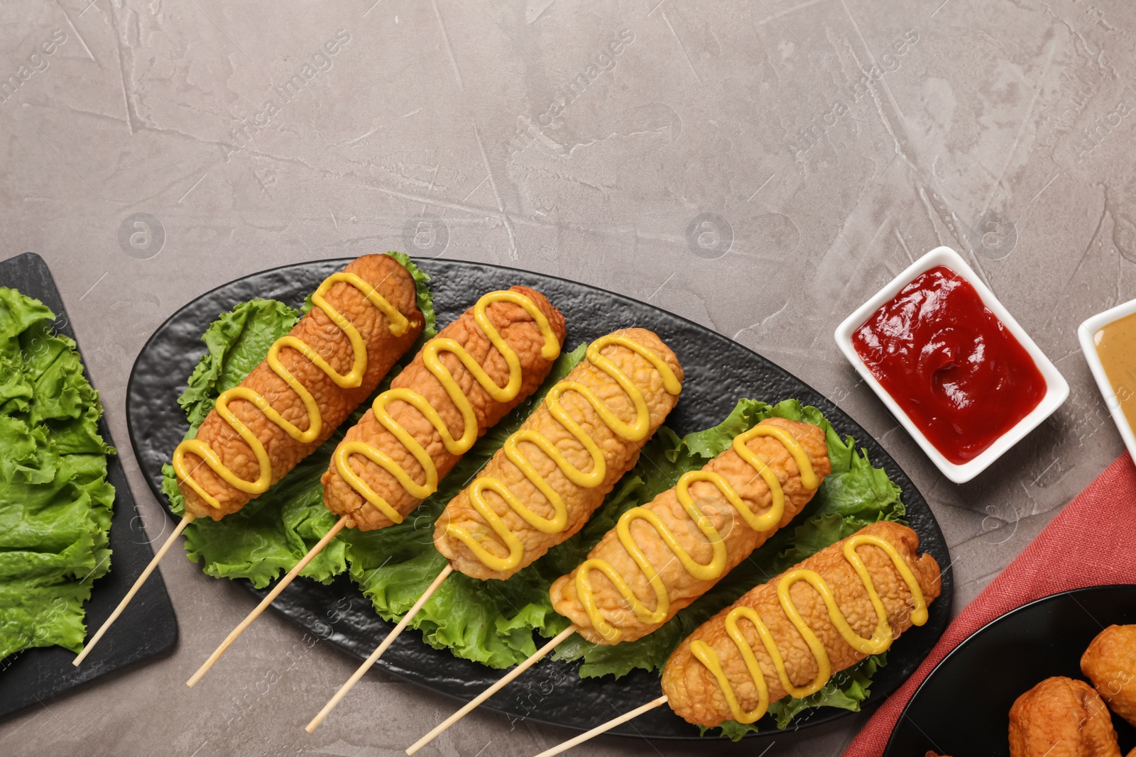 Photo of Delicious corn dogs with mustard served on grey table, flat lay