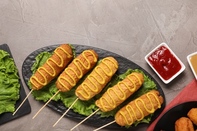 Delicious corn dogs with mustard served on grey table, flat lay