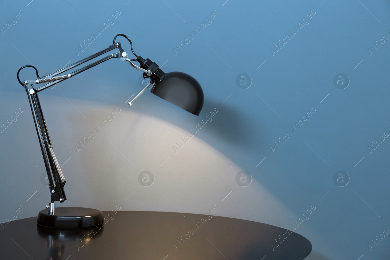 Photo of Modern lamp on table against color background. Space for text