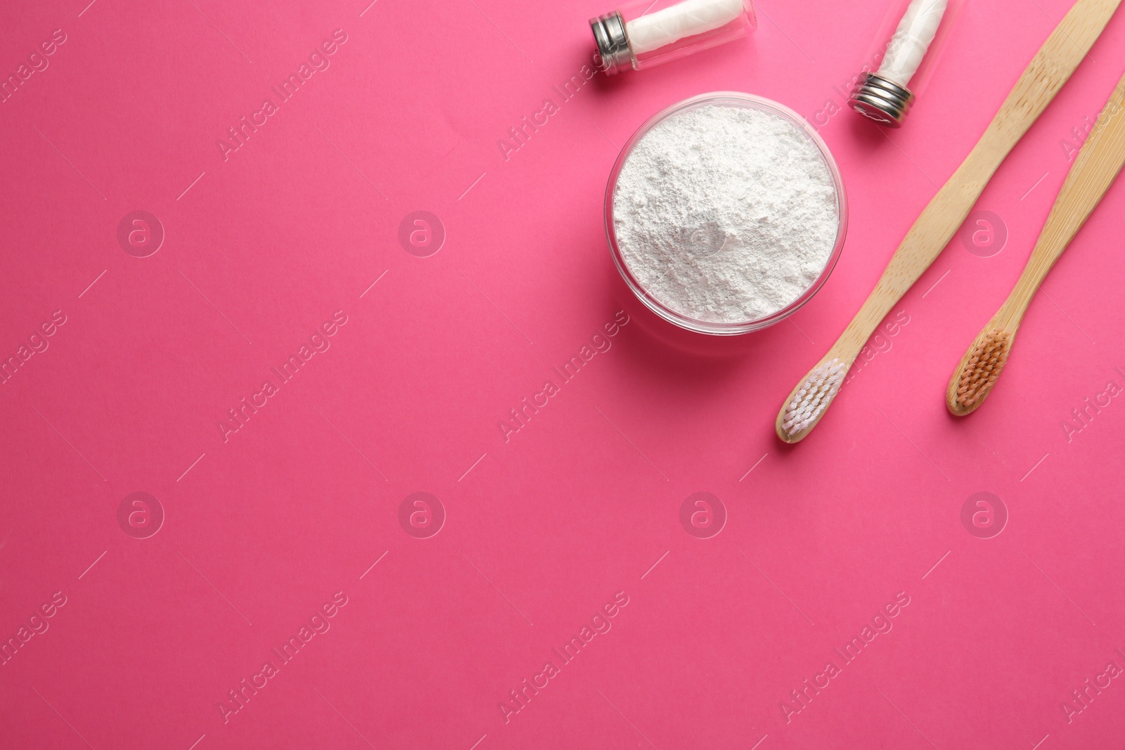 Photo of Bowl of tooth powder, brushes and dental flosses on pink background, flat lay. Space for text